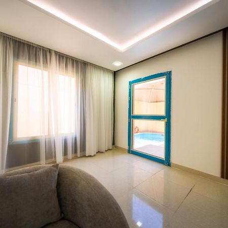 Mirada Gold Jizan - Resort & Private Pools Exterior foto The photo shows a modern interior space that appears to be a room in a home or a building. There is a large window with sheer curtains letting in natural light, which contributes to a bright and airy atmosphere. On one side of the room, there is a sl
